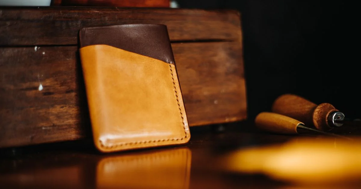 Two-tone stitched leather card wallet on a workbench, the material choice that sets the price of an affordable smart wallet