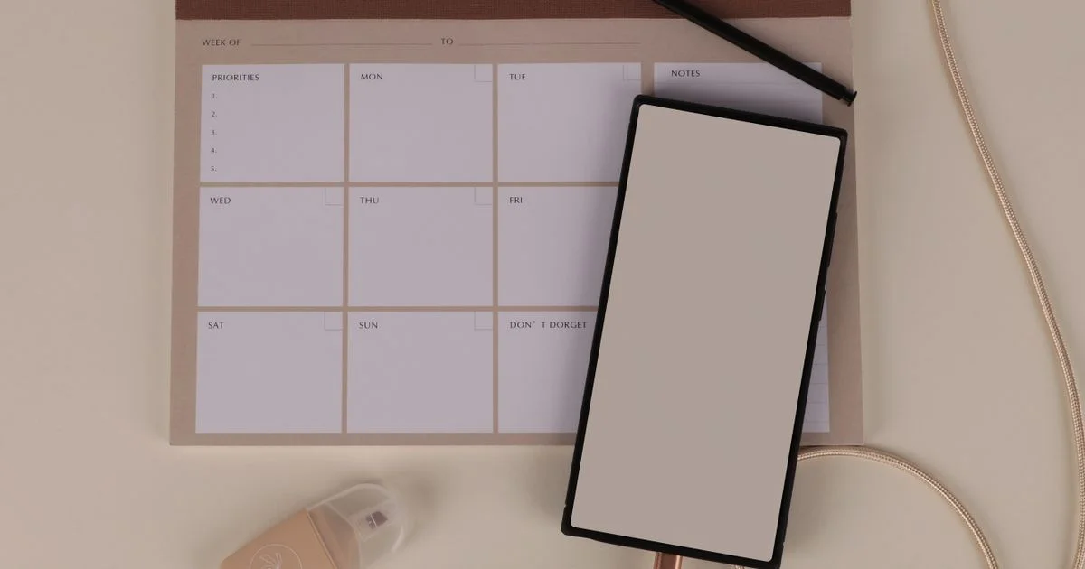 One of the best budget planners open on a desk next to a phone and pen