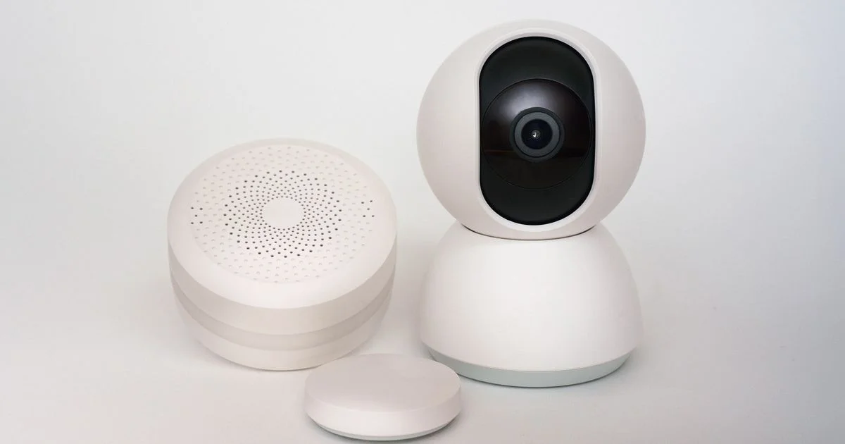 Round smart smoke and CO detector shown alongside a security camera and motion sensor, part of a connected smart home safety set