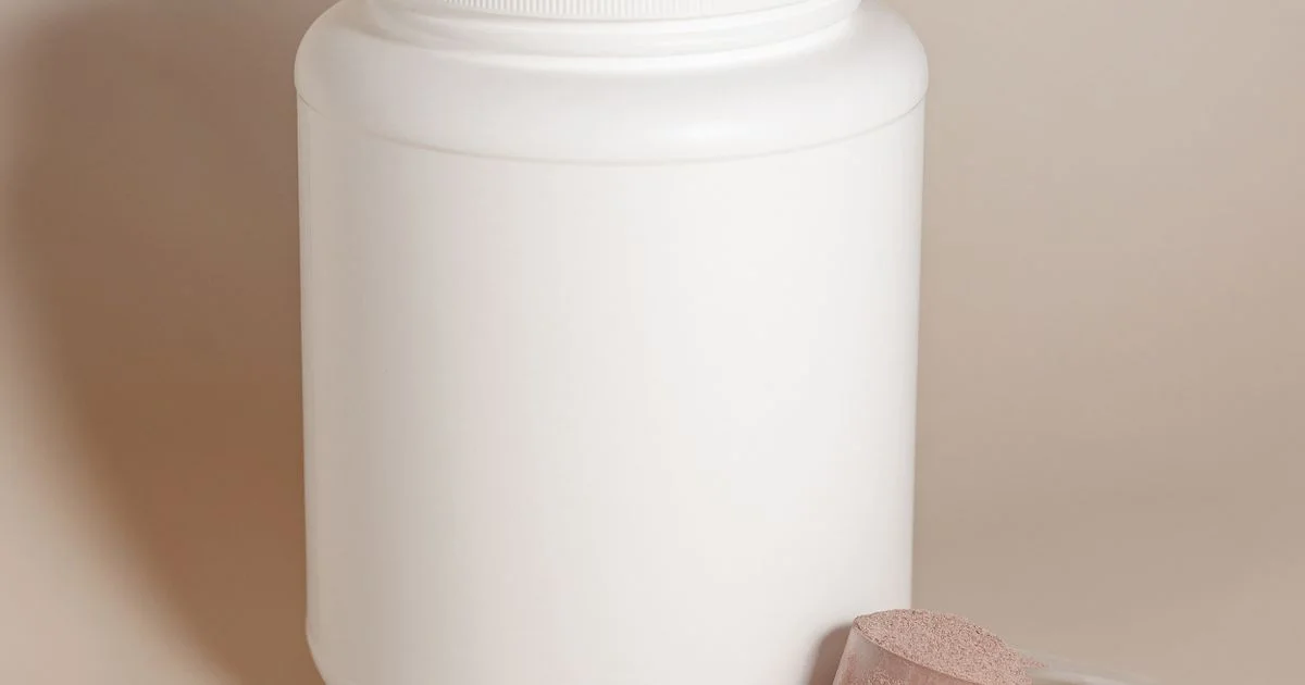 Cheap plant based protein powder in a plain white tub with a scoop of powder beside it