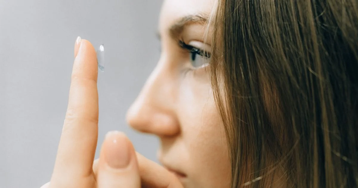 A person placing a contact lens on a fingertip, the daily routine behind buying contact lenses online under $30