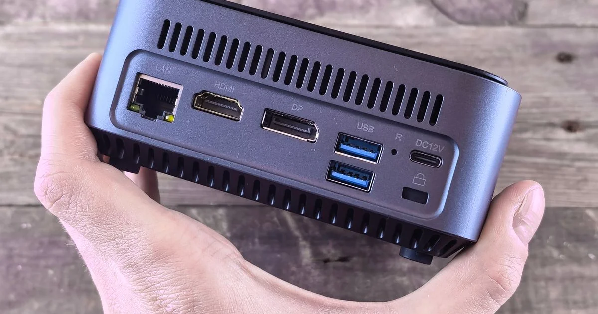 The rear ports of a compact mini PC held in one hand, the case check behind the question is Acemagic mini PC worth it
