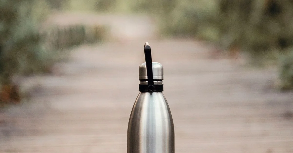 A plain stainless steel bottle on a path, the cheaper option behind asking is smart water bottle worth it
