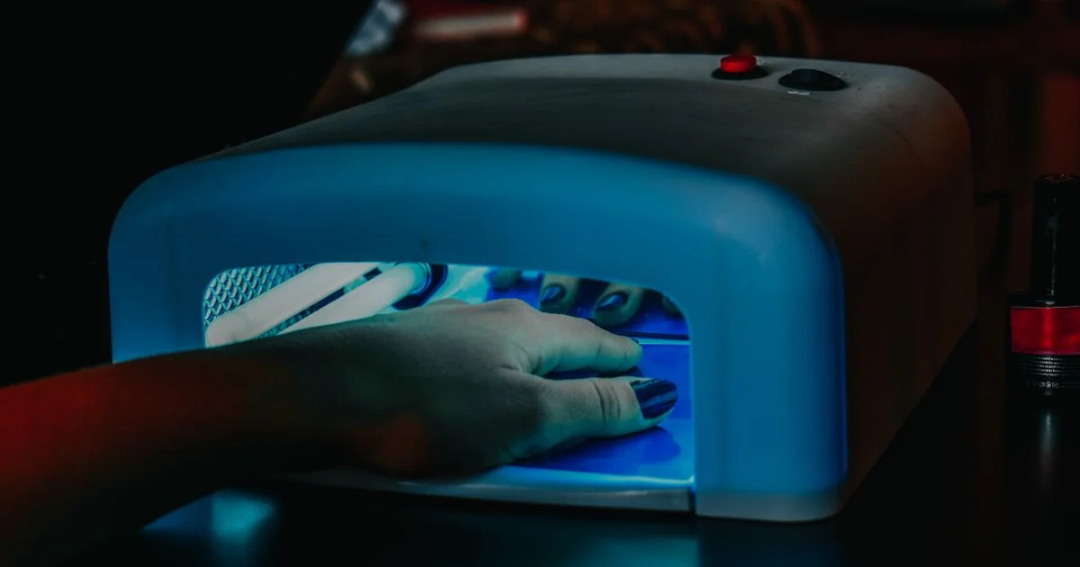 Hand curing gel polish under a UV nail lamp device