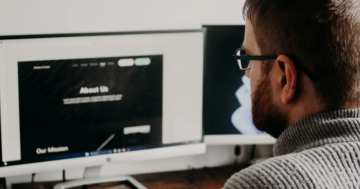 A person building a website page on a desktop monitor, the work behind any website builder price comparison