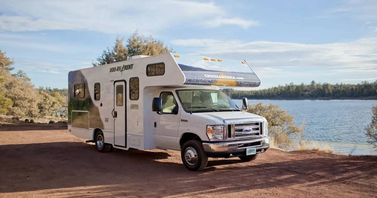 A Class C motorhome parked beside a lake, the picture behind the question Is buying an RV worth it?