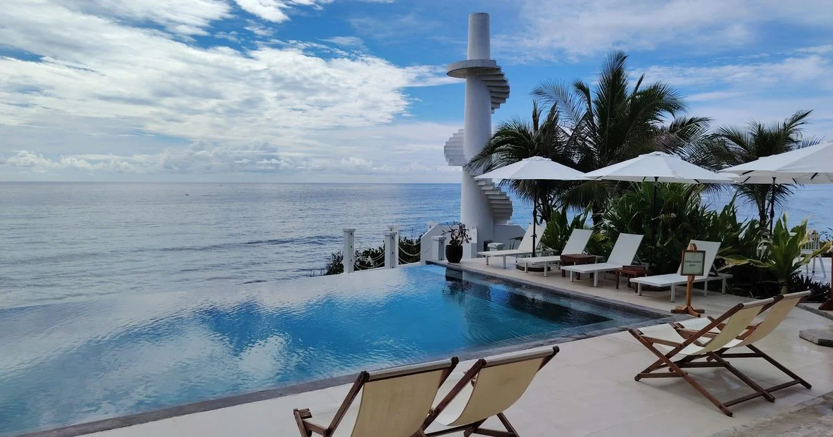 An infinity pool with loungers and umbrellas above the ocean, the lodging layer of luxury vacation packages deals 2026